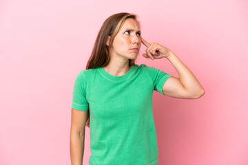 Young English woman isolated on pink background making the gesture of madness putting finger on the...
