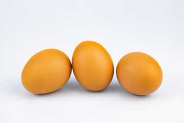 3 fresh chicken eggs lie on a white background, close-up.
