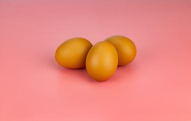 3 chicken eggs on a pink background 