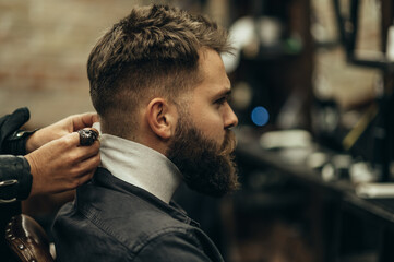 Man is being prepared for a haircut while sitting in chair at barbershop