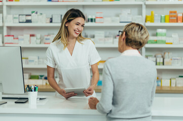 Male pharmacist selling medications at drugstore to a senior woman customer - obrazy, fototapety, plakaty