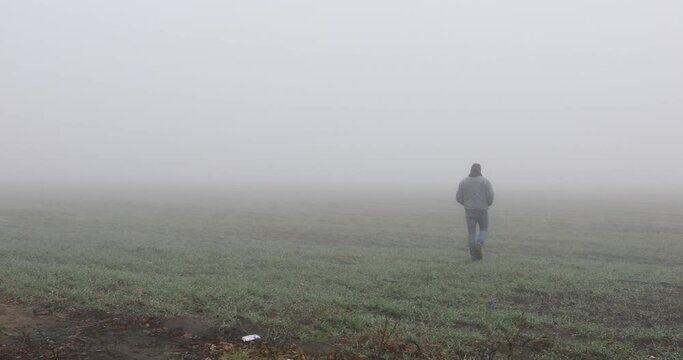 Fog landscape. Man walking  alone on scary foggy misty road. 