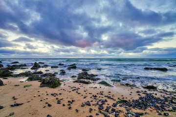 Landscape, seascape sunset on the coast of Huisduinen, the Netherlands. long exposer of waves, dramatic sky, detailed, seaweed, rocks