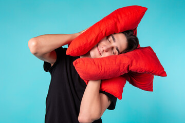 Sleepy cute man with red pillows on a blue background.