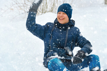 Fototapeta na wymiar a boy plays snowballs outside, beautiful winter weather and white snow around