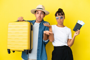 Young traveler friends holding a suitcase and passport isolated on yellow background having doubts...