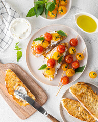 Bruschetta with cream cheese and grilled cherry tomatoes with basil on a light plate on a white background