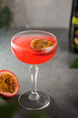 Passion fruit cocktail in a transparent glass on a gray background