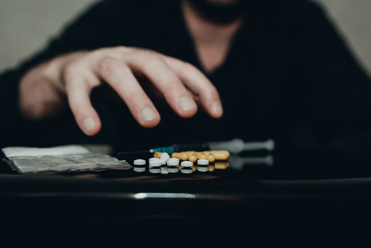 Drug addict hand reaches for heroin drugs with desire or overdose at home dark living room.Toned.Selective focus.