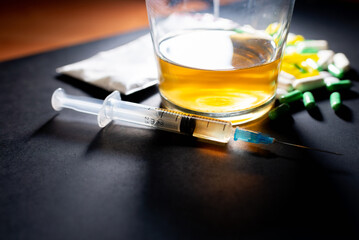 Hard drugs and alcohol on dark gray table. Alcohol pills syringe plastic bag powder of cocaine on...