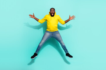 Full length of carefree cheerful millennial youth guy jump autumn travel isolated over cyan color background