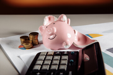 Broken piggy, calculator and coins on business diagram. Investment and bankruptcy concept