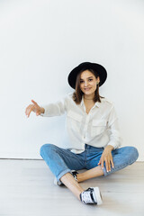 portrait of a beautiful fashionable young woman in jeans and a black hat