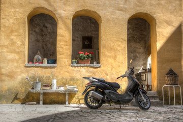 Obraz na płótnie Canvas Istria, Croatia - View of a scooter parked in front of an old yellow house in the ancient town of Oprtalj