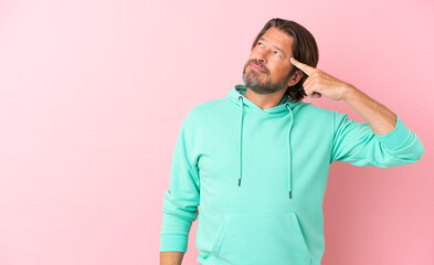 Senior dutch man isolated on pink background making the gesture of madness putting finger on the...