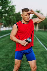 Fototapeta premium Cheerful sporty man in the park on green grass doing exercises