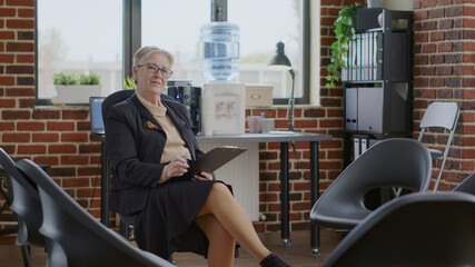 Portrait of woman psychologist holding clipboard in circle with chairs for aa group meeting....
