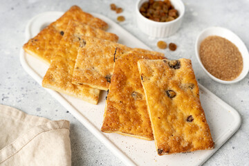 Layered dessert with raisins in a white plate on a light gray culinary background. Delicious homemade sweet puff pastry