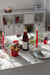 winter holidays, dinner party and celebration concept - christmas table serving with candles, crockery and wine at home