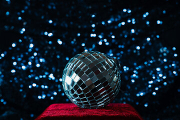 disco ball on red velvet podium on blue sequin background