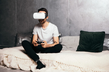 Fototapeta premium Full length portrait of young man wear VR headset. Bearded male in virtual reality glasses playing video games, open mouth wondering. Future technology concept. Virtual life gadget.