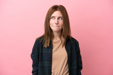 Fototapeta premium Young English woman isolated on pink background having doubts while looking up