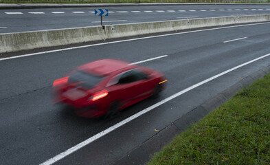 Red car driving fast on the curve of road