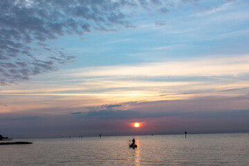 Vivid sunrise clouds over man fishing in the Atlantic Ocean from Higgs Beach in Key West, Florida,...