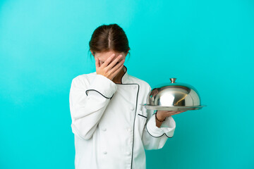 Young chef woman with tray isolated on blue background with tired and sick expression