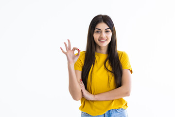 Young female with OK gesture winking isolated on white background