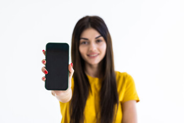 Happy beautiful young woman holding blank screen mobile phone and pointing finger over white background