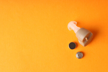 Concept of health care with hearing aid on orange background