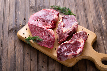 Fresh beef pieces on cutting board, delicious looking ready for steak, with pepper and salt,...
