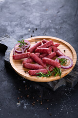 Fresh sausages and ham slices on wooden cutting board, delicious snack, spicy and high quality meat...