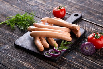 Fresh sausages and ham slices on wooden cutting board, delicious snack, spicy and high quality meat...