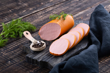 Fresh sausages and ham slices on wooden cutting board, delicious snack, spicy and high quality meat...