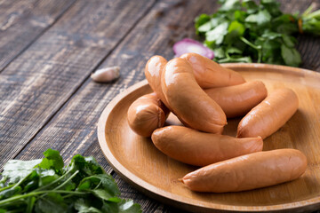 Fresh sausages and ham slices on wooden cutting board, delicious snack, spicy and high quality meat products made of pork and veal, beef.
