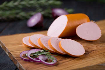 Fresh sausages and ham slices on wooden cutting board, delicious snack, spicy and high quality meat...