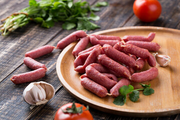 Fresh sausages and ham slices on wooden cutting board, delicious snack, spicy and high quality meat products made of pork and veal, beef.