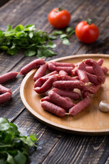 Fresh sausages and ham slices on wooden cutting board, delicious snack, spicy and high quality meat products made of pork and veal, beef.