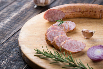 Fresh sausages and ham slices on wooden cutting board, delicious snack, spicy and high quality meat products made of pork and veal, beef.