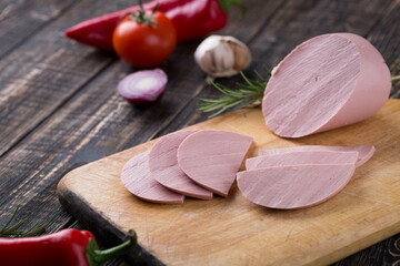 Fresh sausages and ham slices on wooden cutting board, delicious snack, spicy and high quality meat...