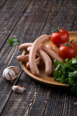 Fresh sausages and ham slices on wooden cutting board, delicious snack, spicy and high quality meat products made of pork and veal, beef.