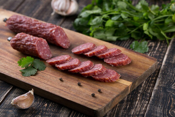 Fresh sausages and ham slices on wooden cutting board, delicious snack, spicy and high quality meat products made of pork and veal, beef.