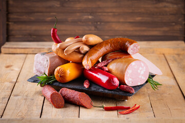 Fresh sausages and ham slices on wooden cutting board, delicious snack, spicy and high quality meat...
