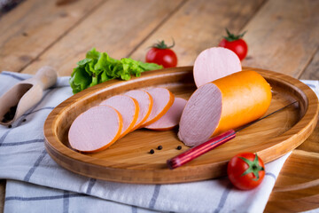 Fresh sausages and ham slices on wooden cutting board, delicious snack, spicy and high quality meat products made of pork and veal, beef.