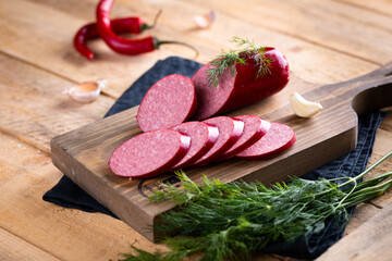 Fresh sausages and ham slices on wooden cutting board, delicious snack, spicy and high quality meat products made of pork and veal, beef.