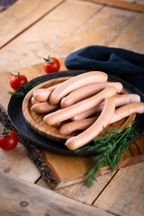 Fresh sausages and ham slices on wooden cutting board, delicious snack, spicy and high quality meat...
