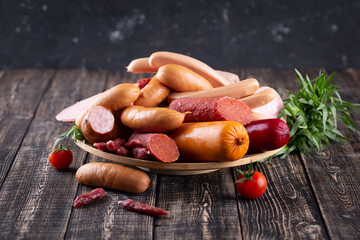 Variety of delicious fresh sausages and hams on wooden cutting board, delicious snack, spicy and...