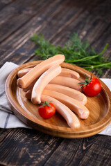 Fresh sausages and ham slices on wooden cutting board, delicious snack, spicy and high quality meat products made of pork and veal, beef.